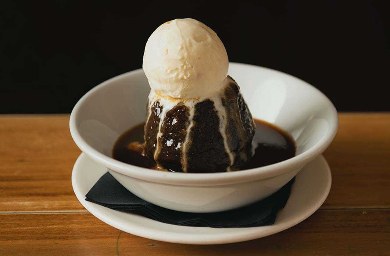Sticky toffee pudding with a ball of ice cream placed on top
