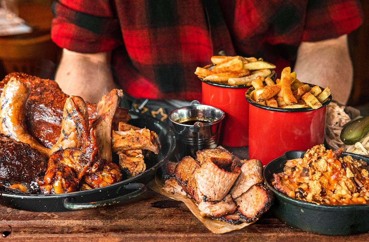 Platter of food including chicken wings, ribs, fries and beans