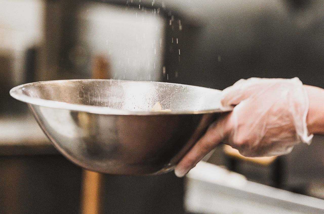 Sprinkling flour into a silver bowl in a kitchen