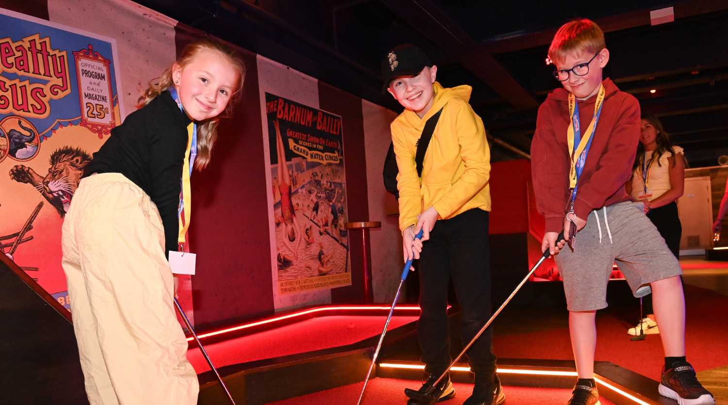 A group of children enjoying playing indoor mini golf