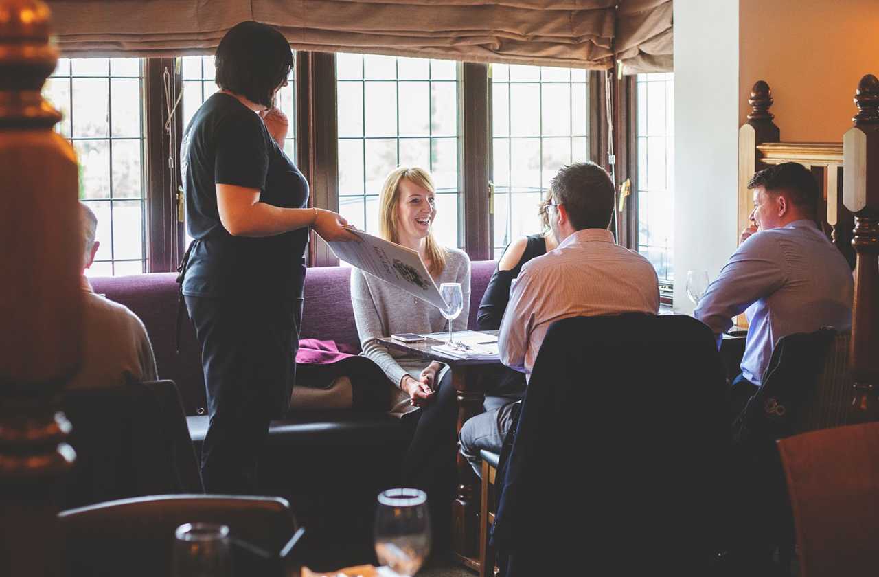 Waitress serving a table of guests in the pub