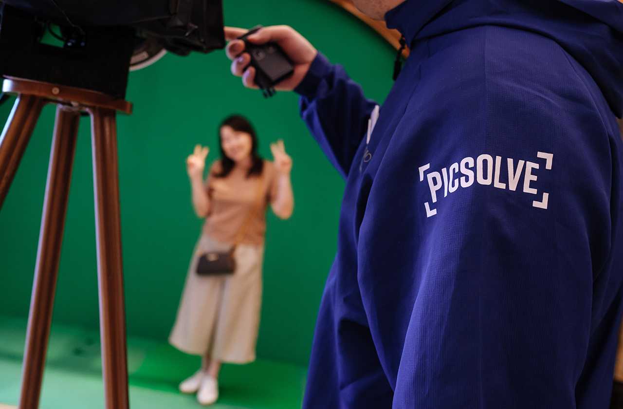 Guest having their photo taken against a green screen by a Picsolve team member